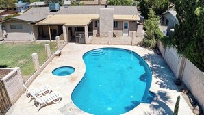 A residential backyard with a swimming pool, two lounge chairs, and a covered patio area. - Scottsdale Paradise w/ Fire Pit & BBQ, Heated Pool & Spa, Mini Golf & Cornhole (Scottsdale)
