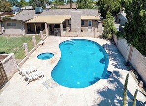 Ein Garten mit Pool, zwei Liegestühlen und einer überdachten Terrasse.