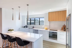 A modern kitchen with a large island, white cabinetry, and stainless steel appliances. - Inner City for Large Groups - Garage Parking (Christchurch)