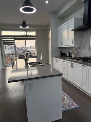 Una cocina moderna con una isla central, armarios blancos y vistas a través del ventanal.