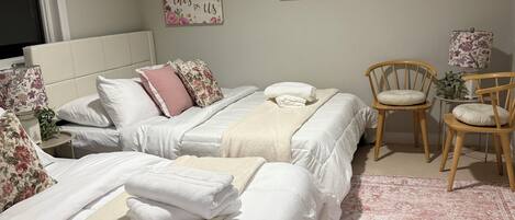 Une chambre d’hôtel avec deux lits, une chaise, une lampe et un tableau encadré au mur.