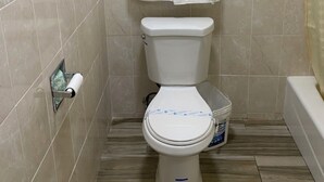 A small bathroom with a toilet, a towel hanging on the wall, and a toilet paper holder.