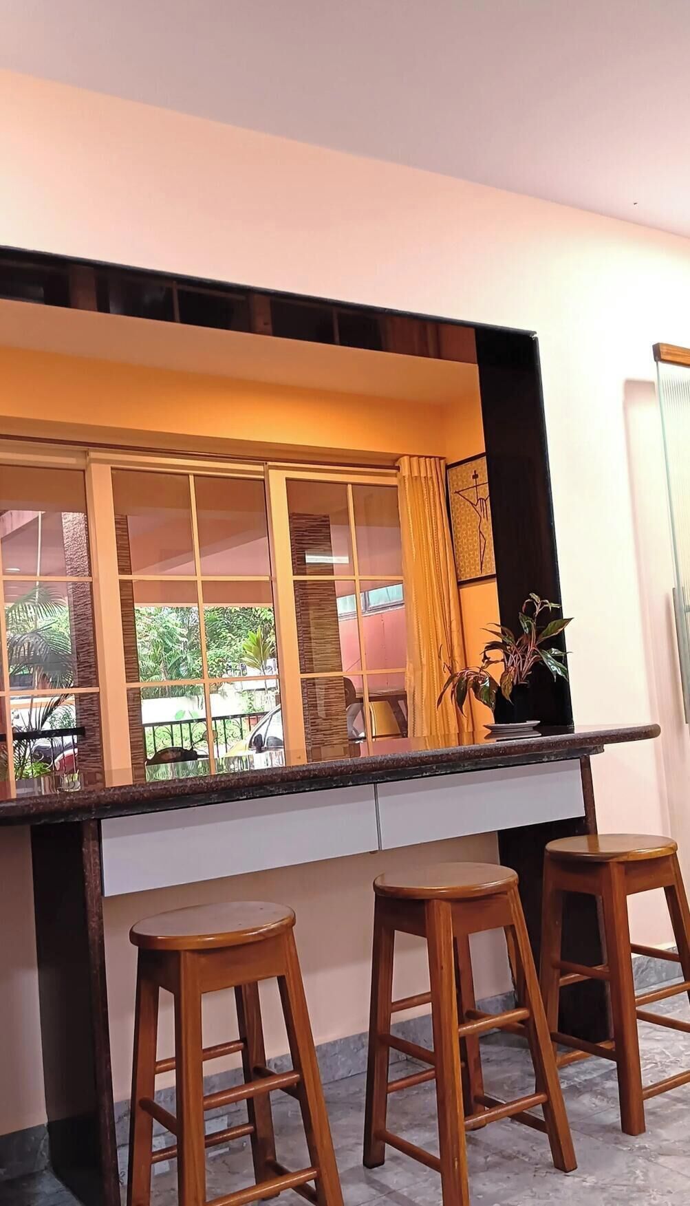 A kitchen with a large window, two wooden stools, and a countertop.