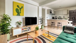 Uma sala de estar moderna com uma televisão de tela plana, um sofá verde e um tapete colorido.
