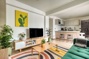 A modern living room with a flat-screen TV, a green sofa, and a colorful rug. - Roma Elegance · Unique Apartment (Ciudad de México)