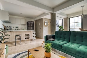 A modern living space with a green sofa, a kitchen area, and a large window. - Roma Elegance · Unique Apartment (Ciudad de México)