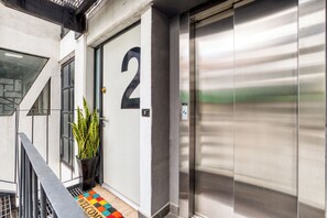 A building entrance with a door marked with the number 2, a potted plant, a metal gate, and a doormat with 'WELCOME' written on it. - Roma Elegance · Unique Apartment (Ciudad de México)