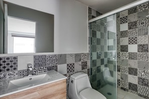 Un baño de diseño moderno, con lavamanos, inodoro y zona de ducha.
