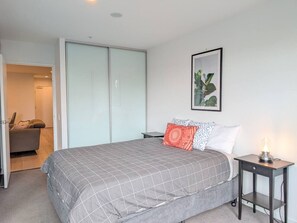 A bedroom with a bed, a nightstand, a framed picture, and a sliding door closet.