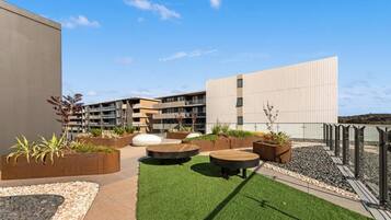 An outdoor patio area with planters, seating, and a building in the background.