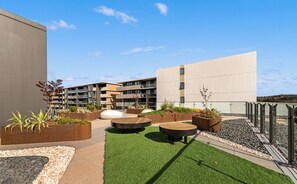 An outdoor patio area with planters, seating, and a building in the background.