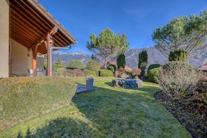 A well-maintained garden with a stone bench, a pergola, and a view of mountains in the background. - Beautiful Family Home with a Pool, Nestled Between the Lake and the Mountains (Lathuile)