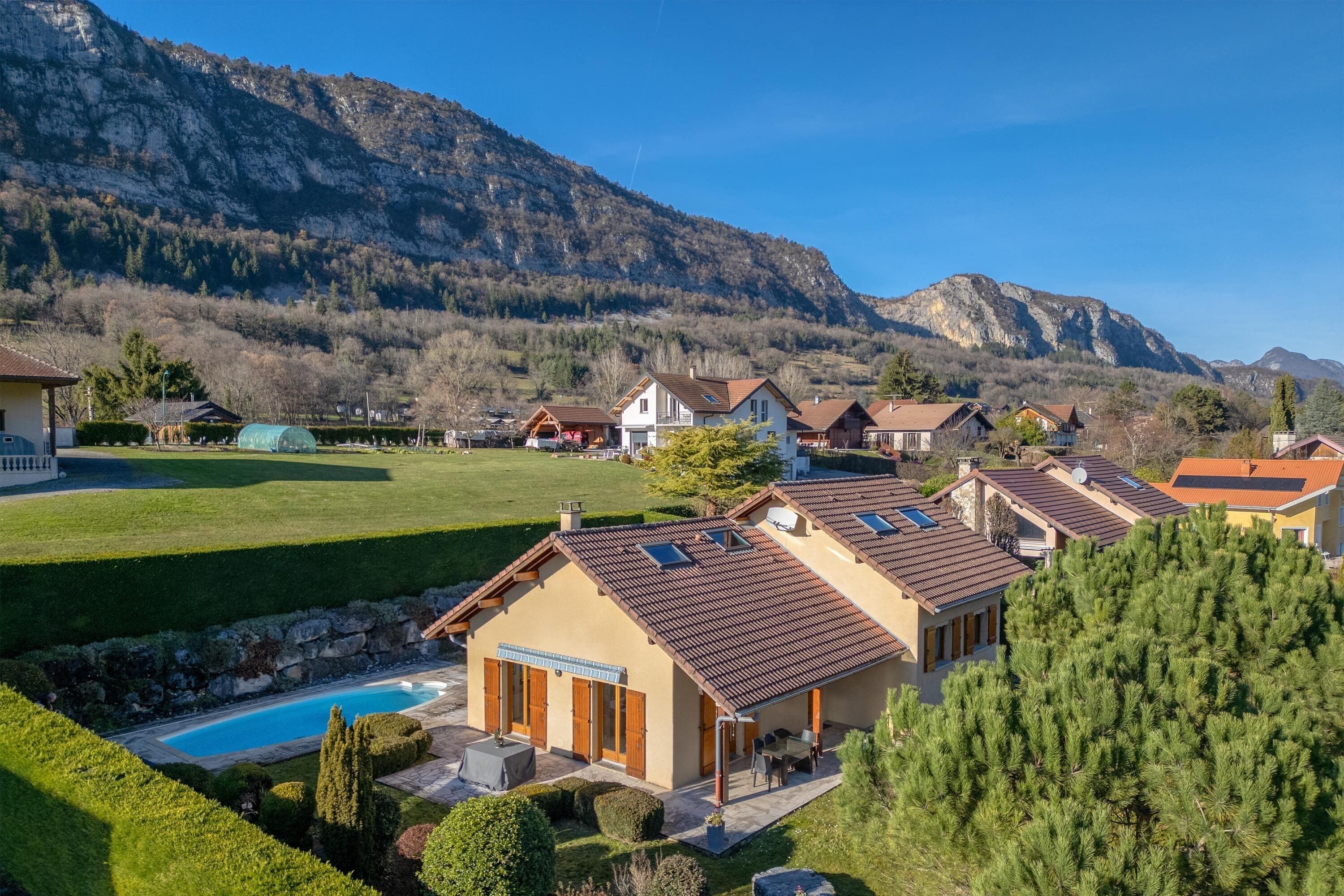 A residential area with houses, a swimming pool, and mountains in the background.