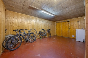 A room with wooden walls and a red floor, containing a white refrigerator and two bicycles. - Beautiful Family Home with a Pool, Nestled Between the Lake and the Mountains (Lathuile)