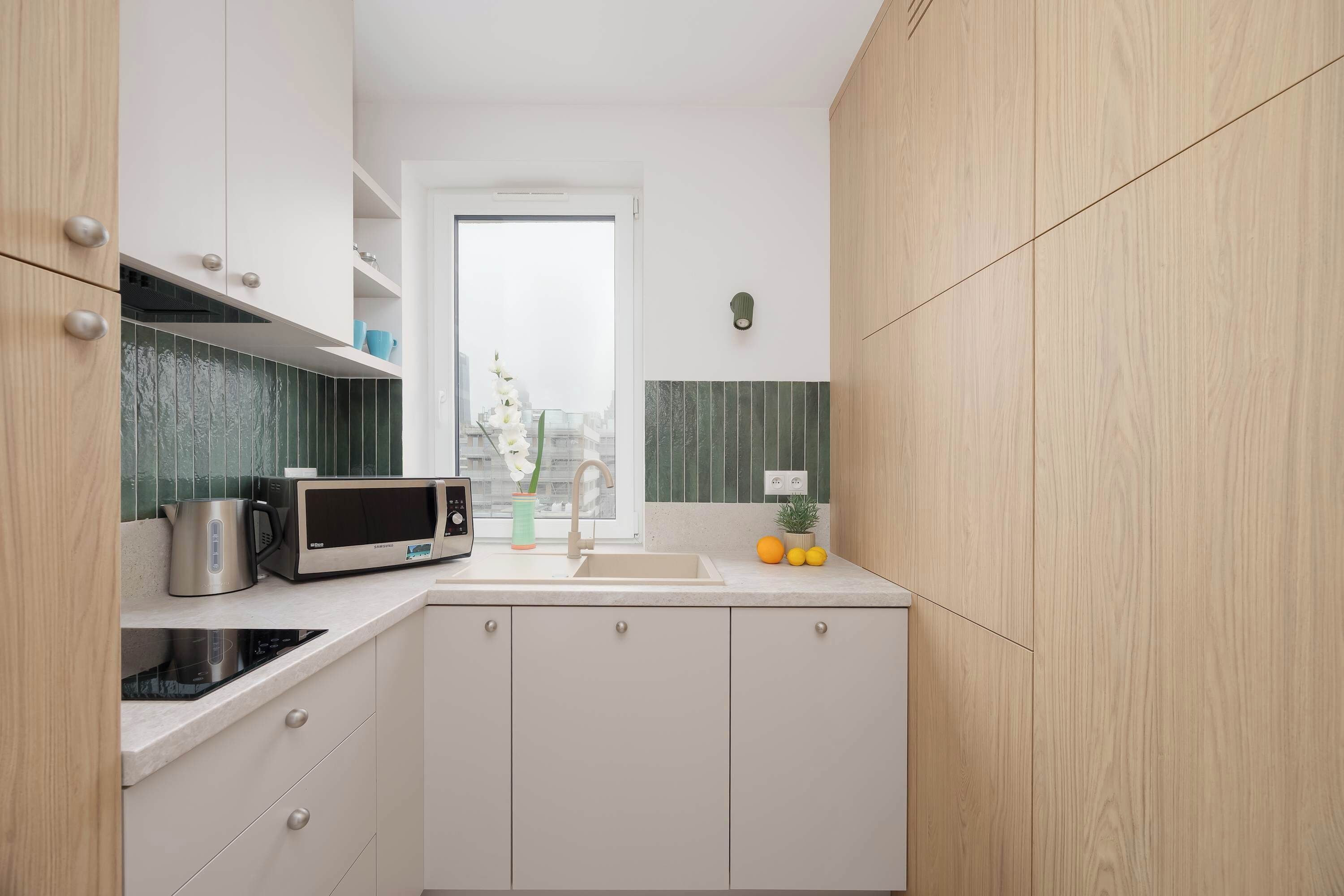 A modern kitchen with white cabinets, a stainless steel microwave, and a sink.