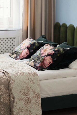 Un lit avec des oreillers à motifs floraux et une couvre-lit matelassée.
