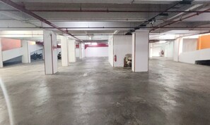 Ruime overdekte parkeerplaats met betonnen vloeren en witte zuilen.
