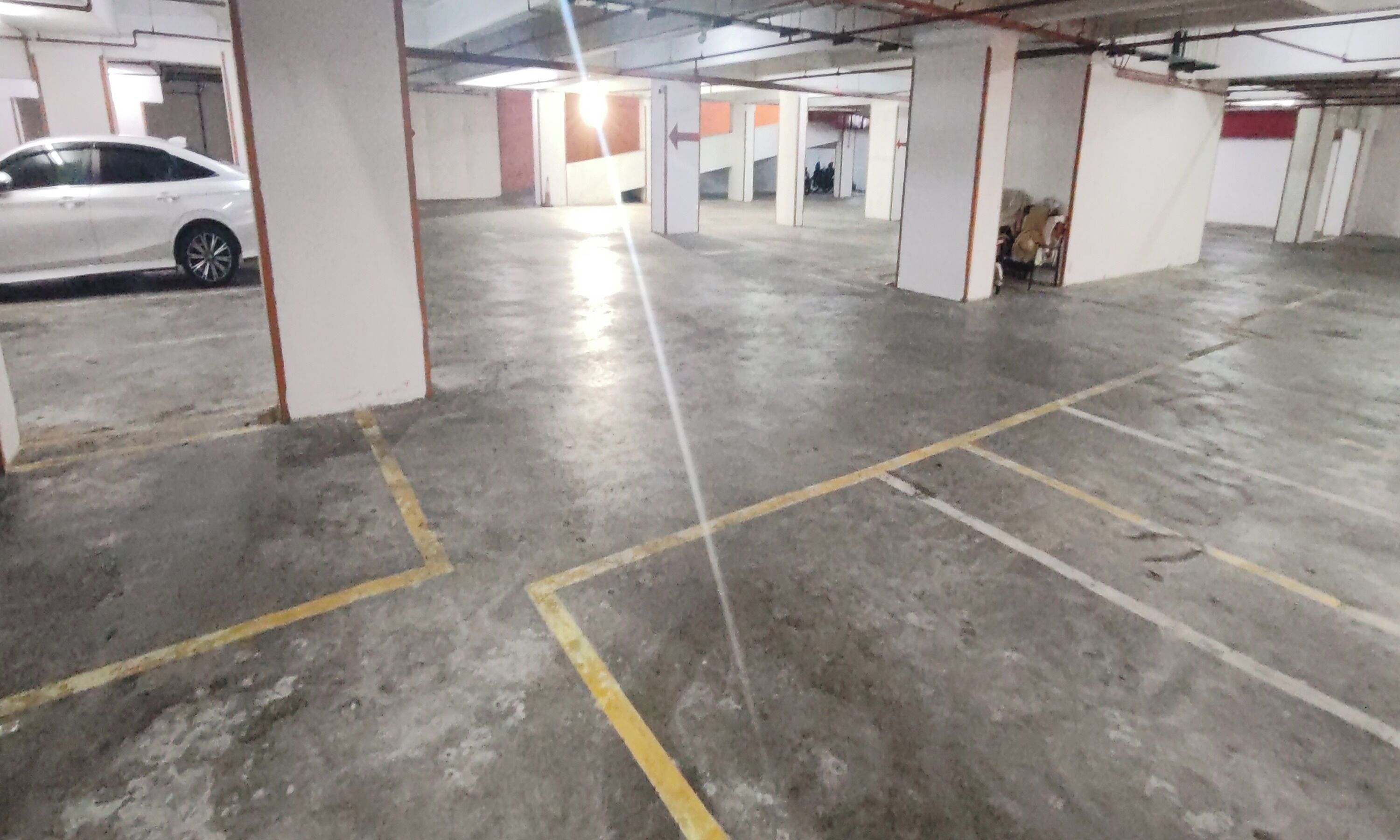 Un estacionamiento con pisos de concreto, espacios delimitados y columnas estructurales.