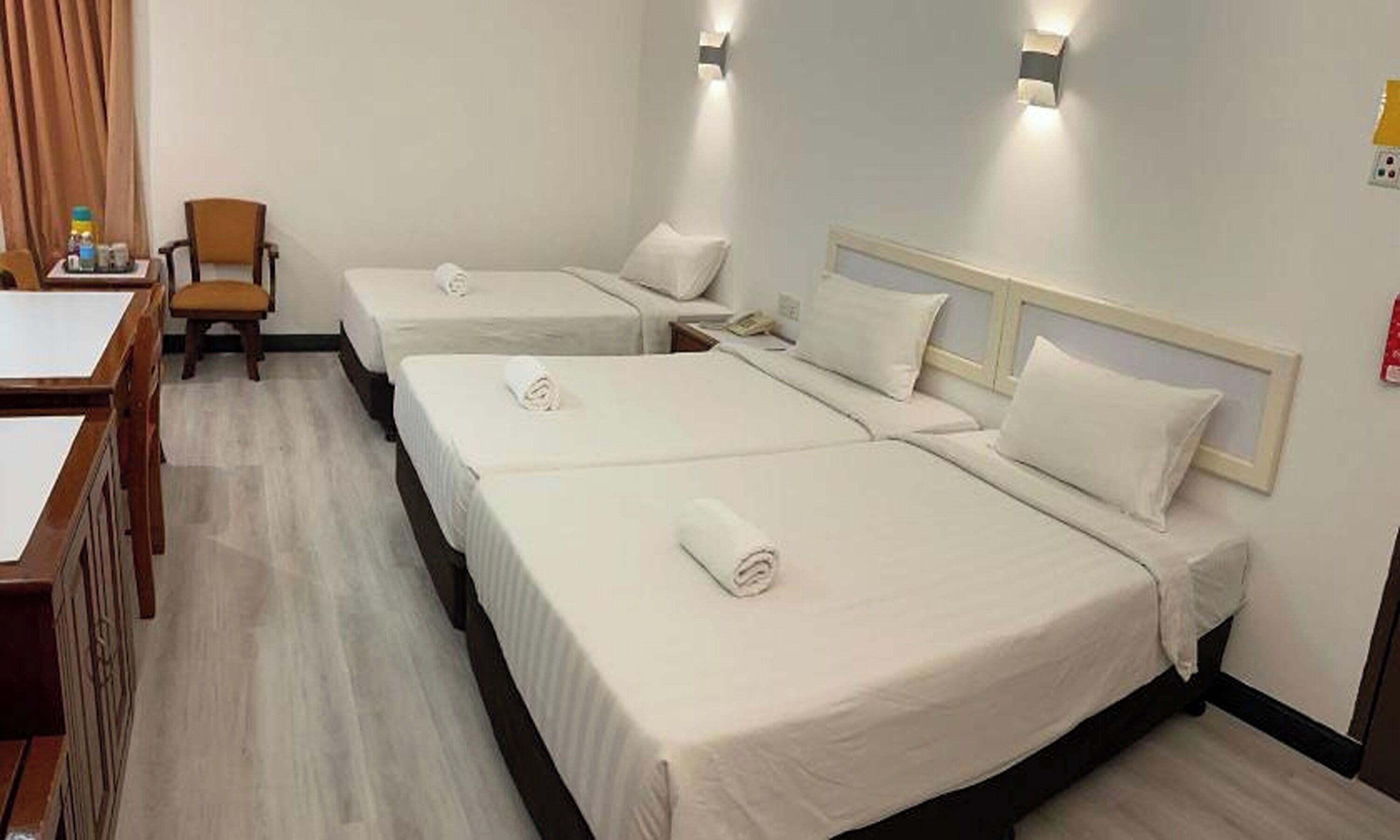 Una habitación de hotel con tres camas, una mesa de comedor y una silla.