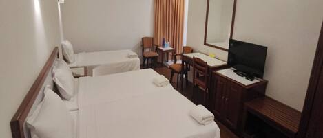 A hotel room with two single beds, a desk with a chair, a television, and a mirror.