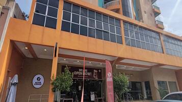A building with a large glass facade, a sign for a coffee shop, and a red banner indicating the establishment is open.