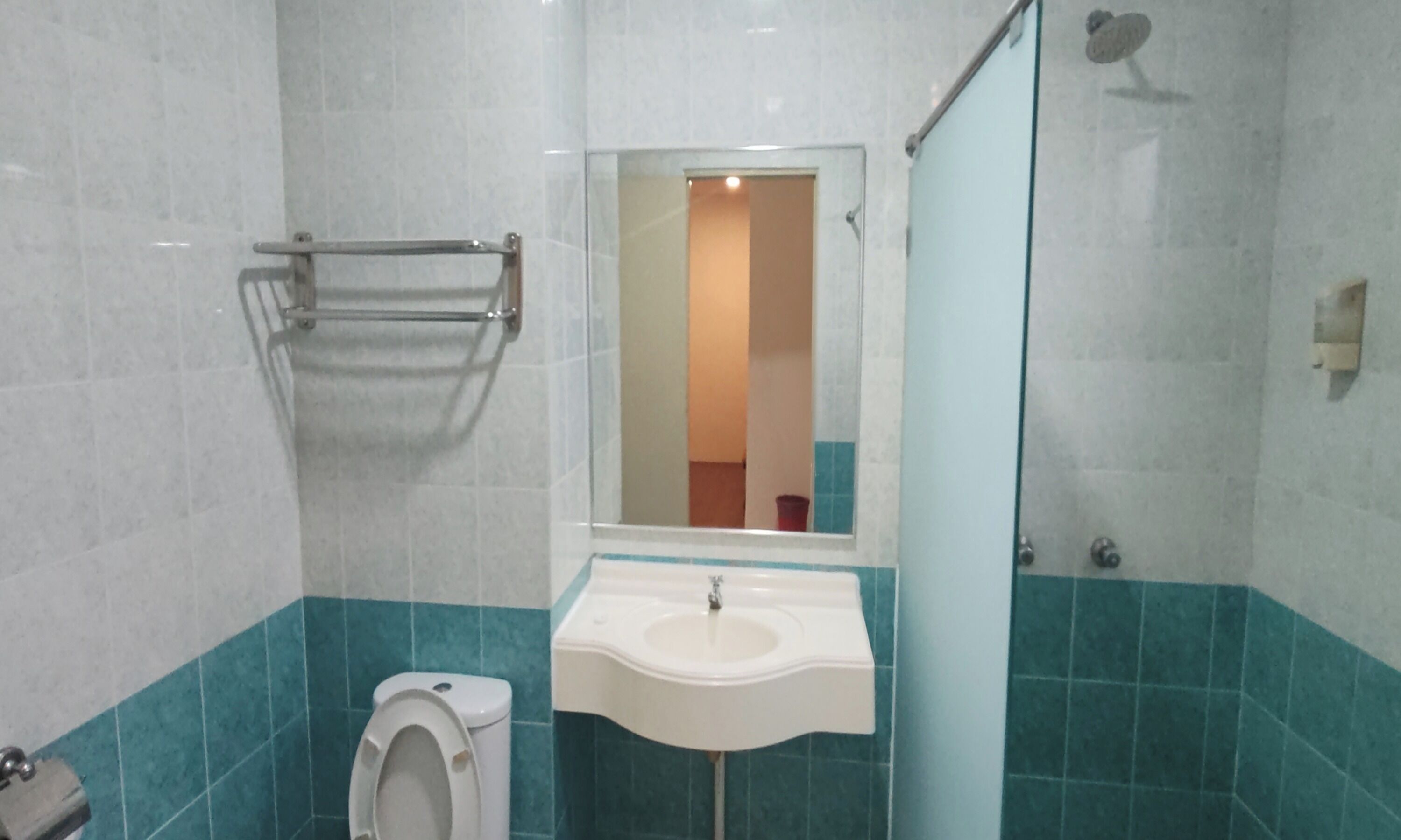 A bathroom with a toilet, sink, and glass shower enclosure.