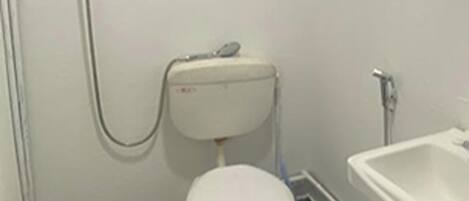 A small bathroom with a toilet, a sink, and a window above the sink.