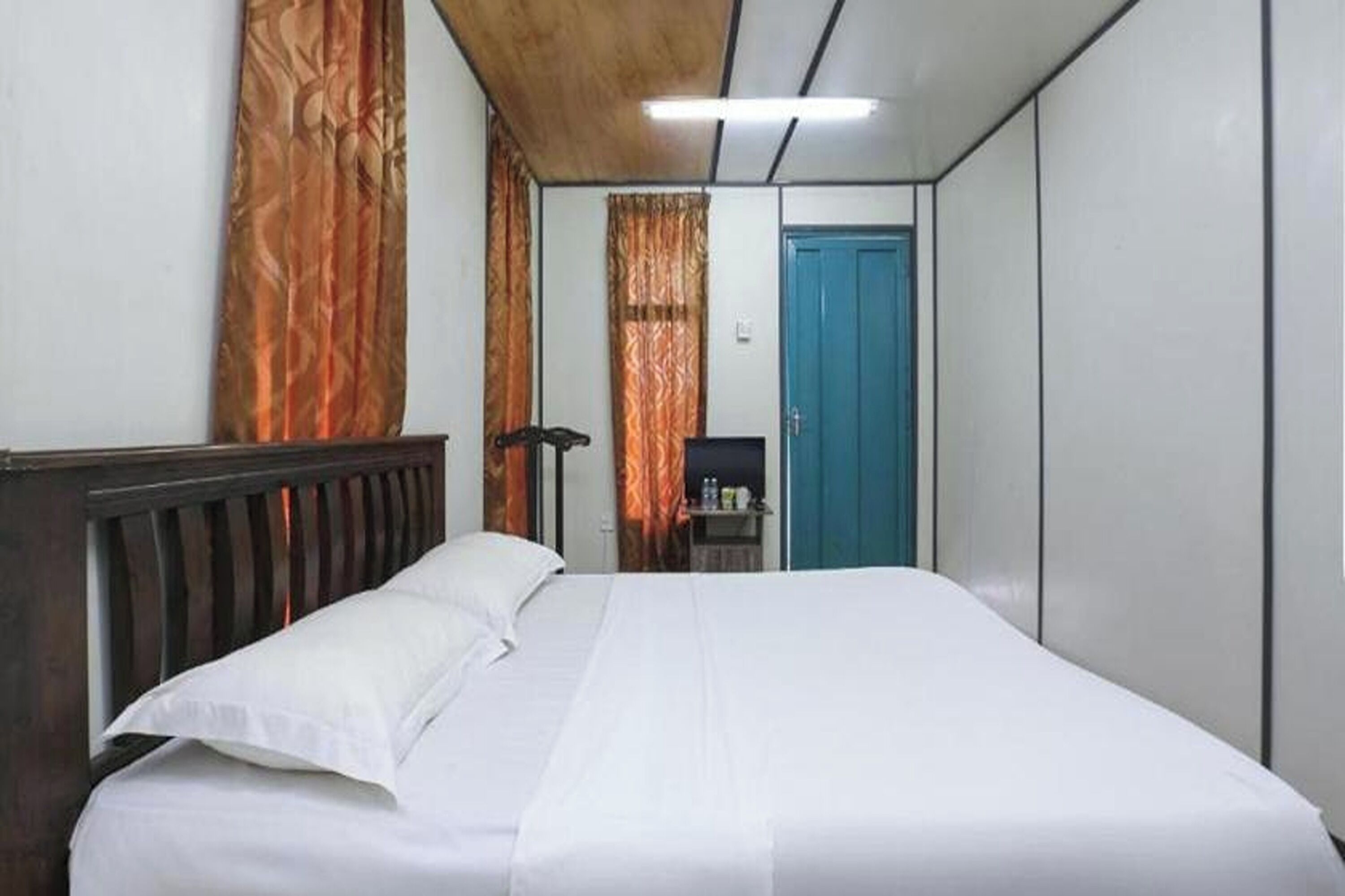 Une chambre d’hôtel avec un lit, un bureau et une porte bleue.