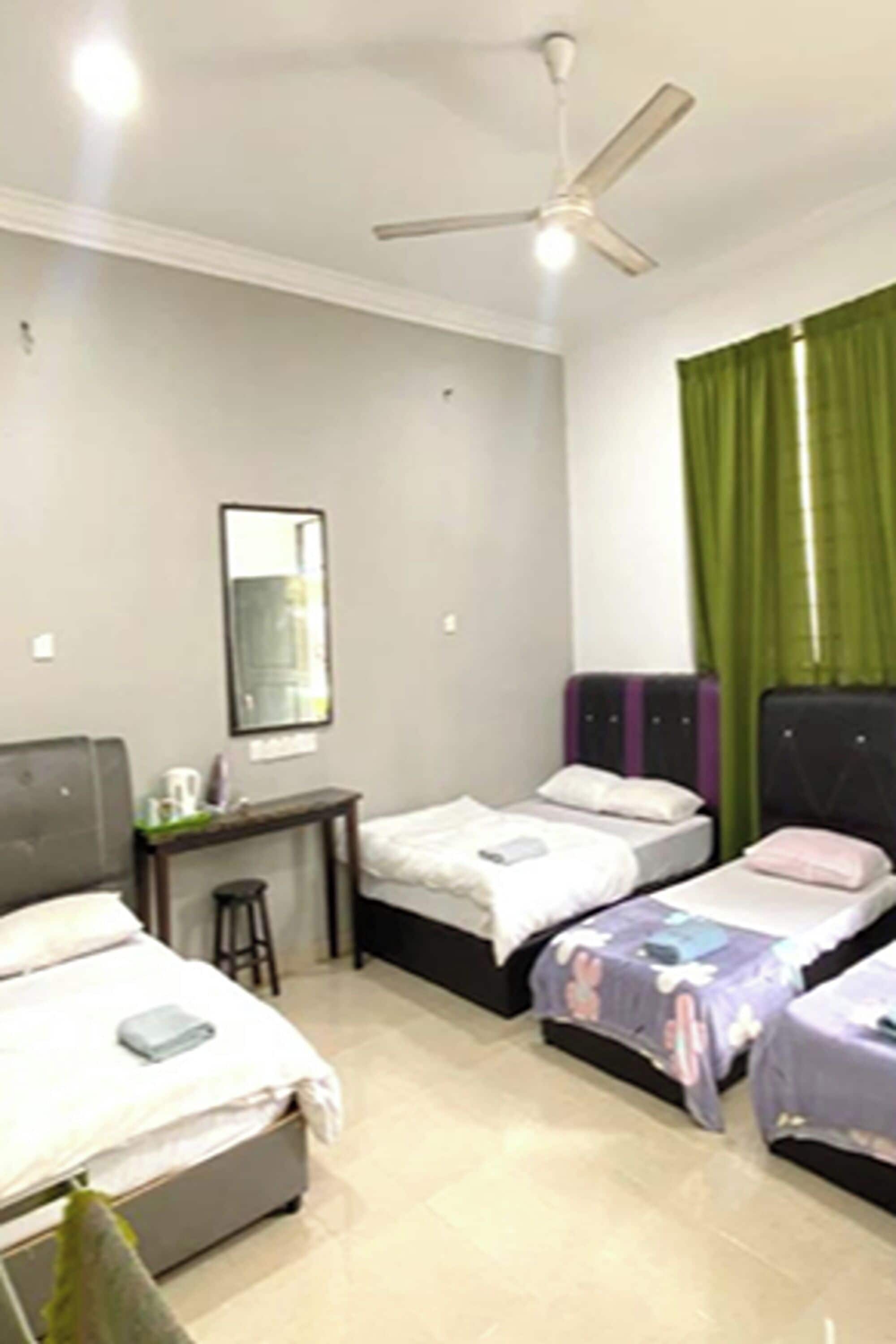 A hotel room with two beds, a desk, and a ceiling fan.