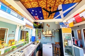 Uma cozinha compacta com geladeira, pia e bancada com banquetas.