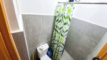 Un baño con inodoro, cortina de ducha y lavamanos azul.