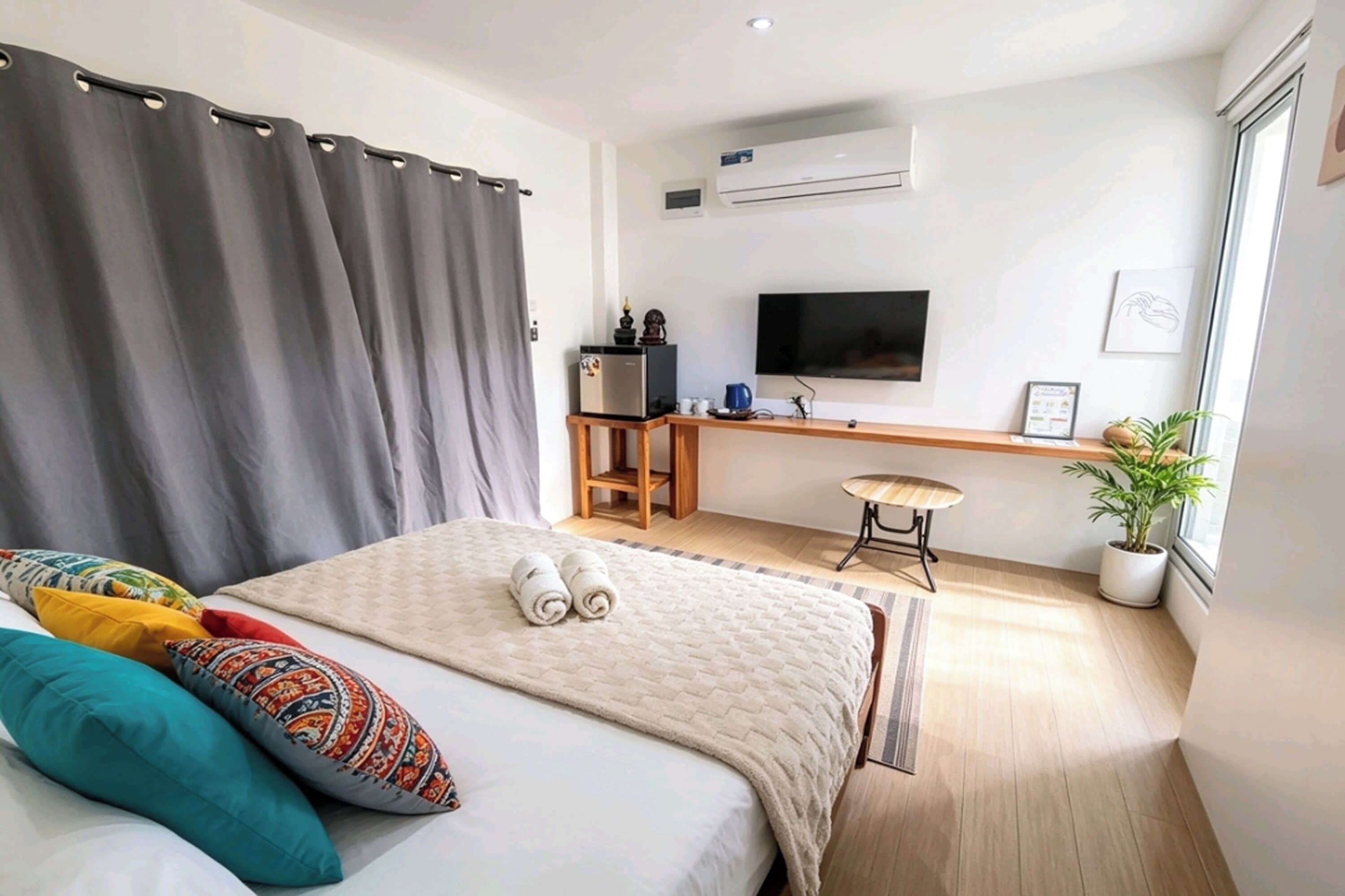 A hotel room with a bed, a desk, a television, and a potted plant.