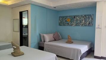 A hotel room with two beds, a painting on the wall, and a notice board.