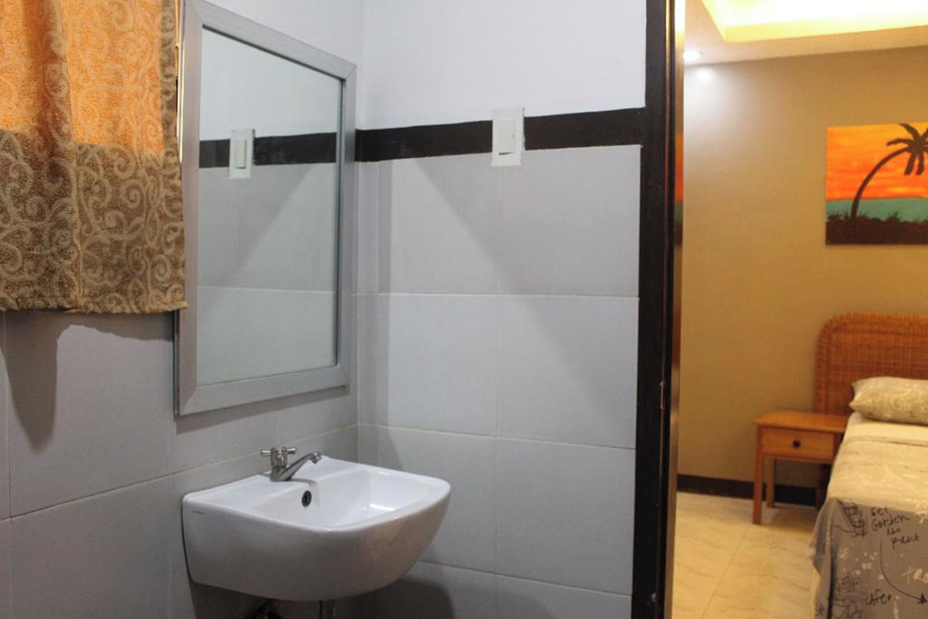 A bathroom with a white sink, a mirror, and a towel hanging on the wall.