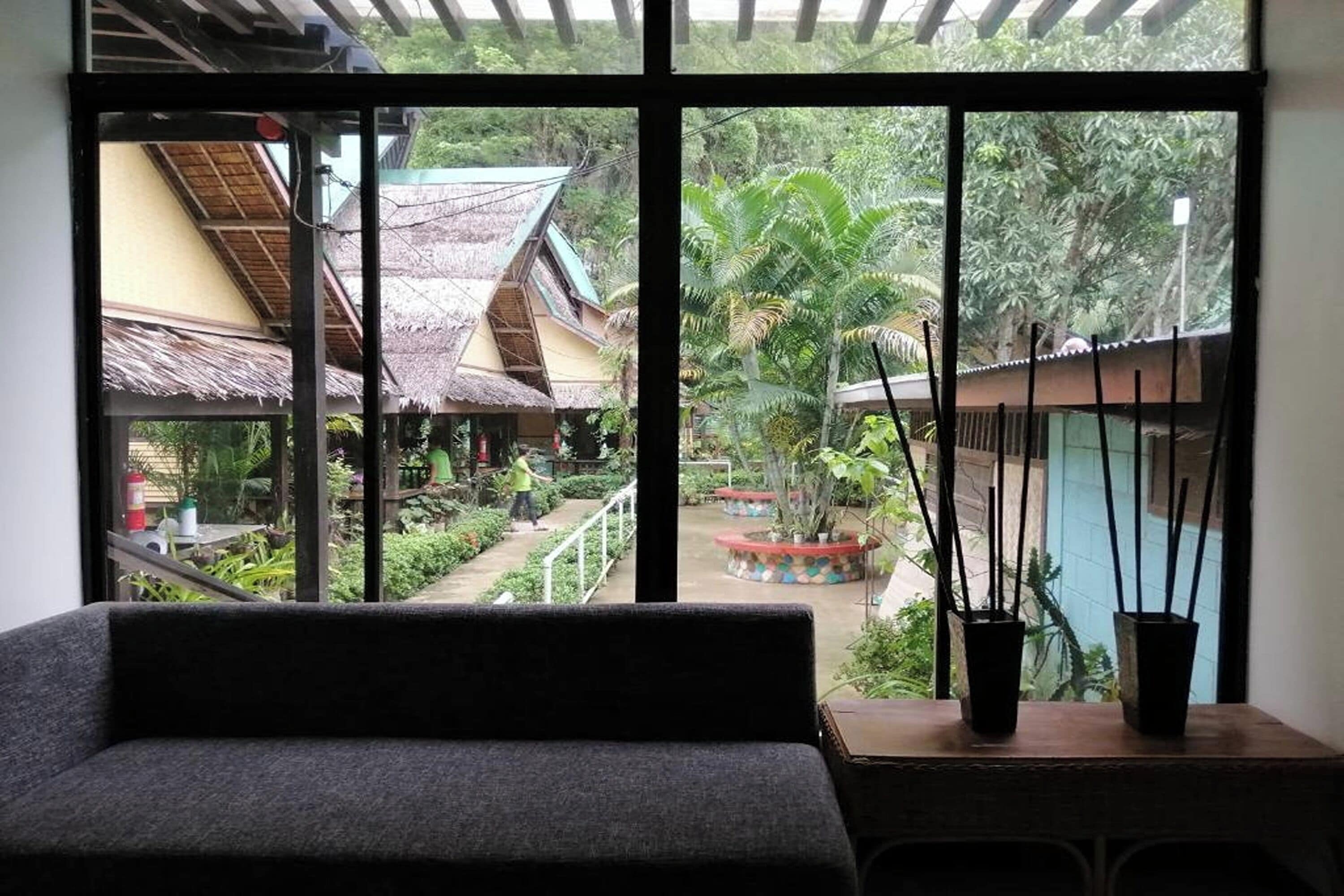 A room with a large window overlooking a courtyard with traditional buildings and plants.