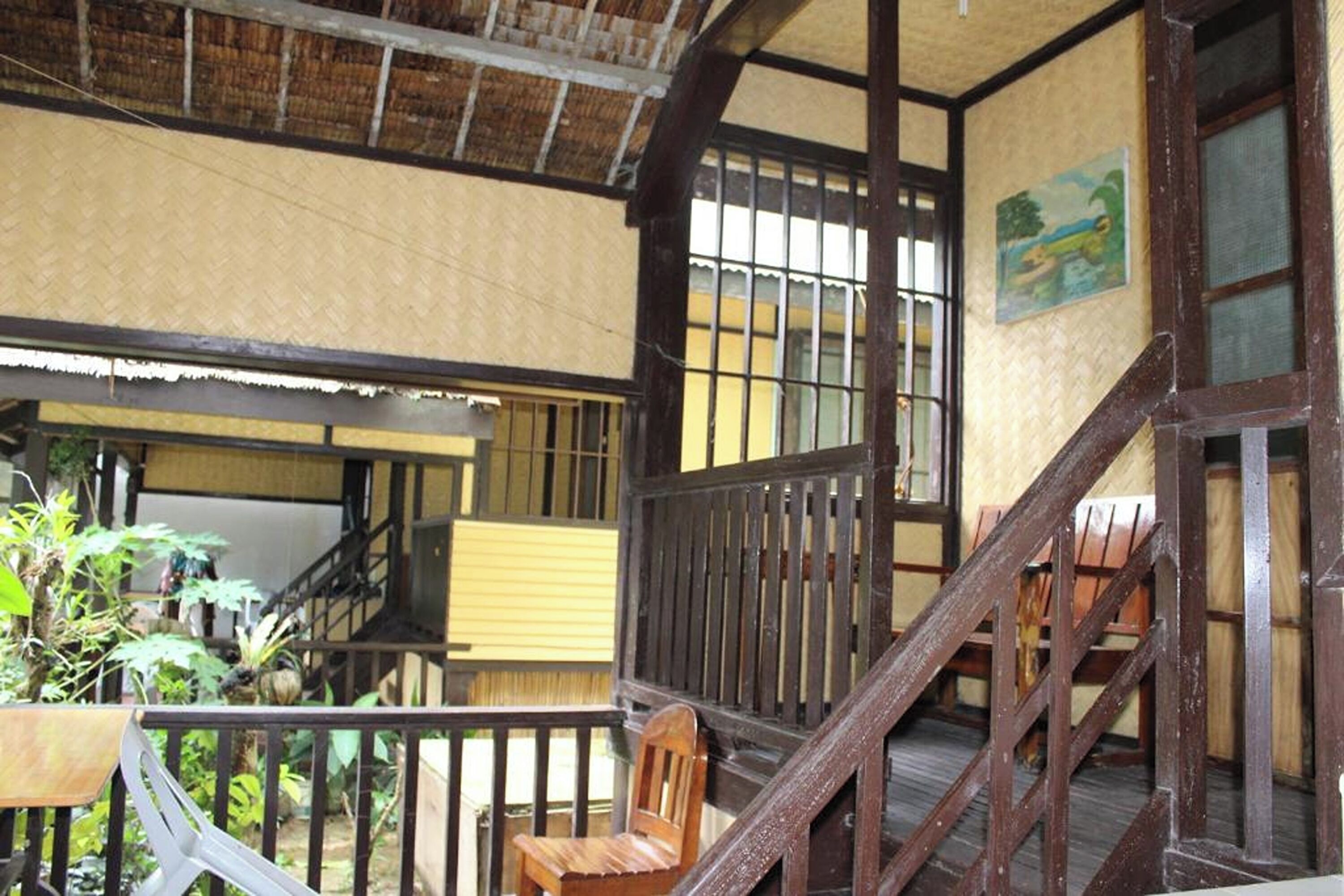 A traditional wooden staircase leading to an upper level with a view of a garden.