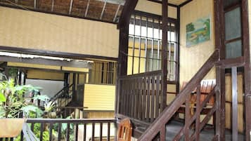 A traditional wooden staircase leading to an upper level with a view of a garden.