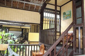 A traditional wooden staircase leading to an upper level with a view of a garden. - Cliffside Cottages (El Nido)