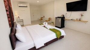 Een hotelkamer met een bed, een bureau, een stoel, een televisie en een koelkast.