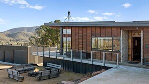 A modern building with a fire pit and outdoor seating area. - Ridge Way Views - Breathtaking Lake Eildon Views (Mountain Bay)