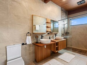 Ein modernes Badezimmer mit Waschbecken-Doppelung, einem Holz-Waschtisch, einem großen Spiegel und einer Duschkabine aus Glas.