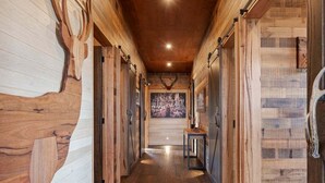 A hallway with wooden walls and a wooden floor, leading to a room with a fireplace. - Ridge Way Views - Breathtaking Lake Eildon Views (Mountain Bay)