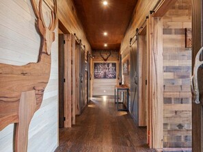 A hallway with wooden walls and a wooden floor, leading to a room with a fireplace. - Ridge Way Views - Breathtaking Lake Eildon Views (Mountain Bay)