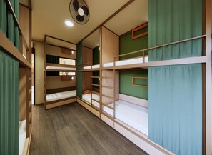 A bunk bed room with a ceiling fan, wooden bunk beds, and green curtains. - Rebel Rooster Hostel (Hanoi)