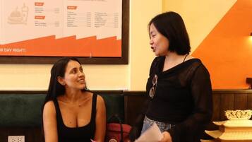 Two individuals seated at a table with a menu in the background.