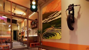 A modern interior with a long wooden table and benches, a large wall painting, and a unique tire mounted on the wall. - Rebel Rooster Hostel (Hanoi)