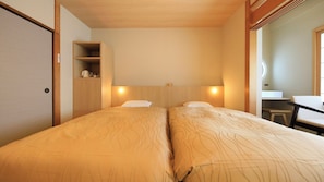 A hotel room with two beds, a wooden headboard, a small desk, and a mirror.