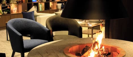 Un interior moderno con una mesa redonda, sillas y una chimenea central.