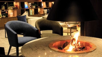 Un interior moderno con una mesa redonda, sillas y una chimenea central.