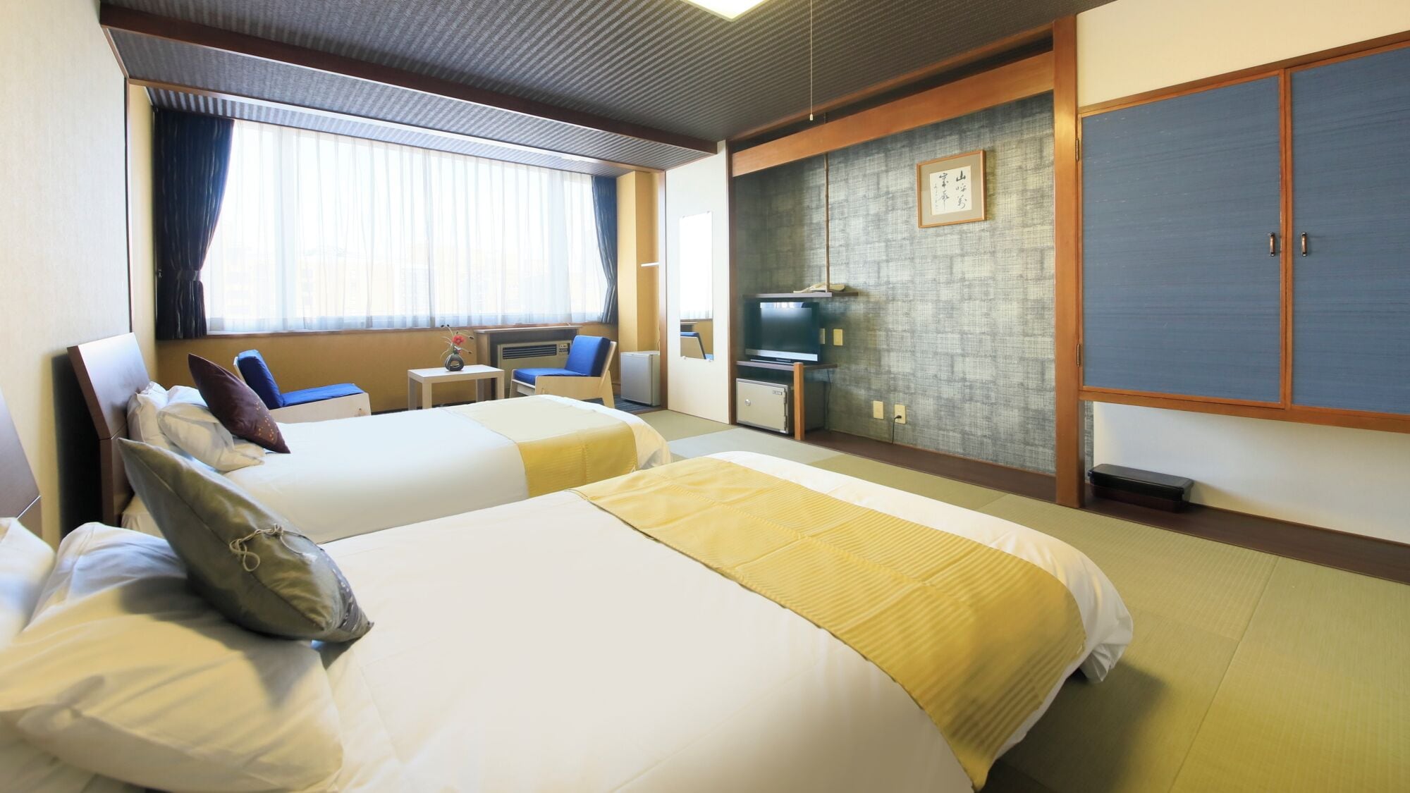 Habitación de hotel con dos camas, televisión, una mesita y un armario.